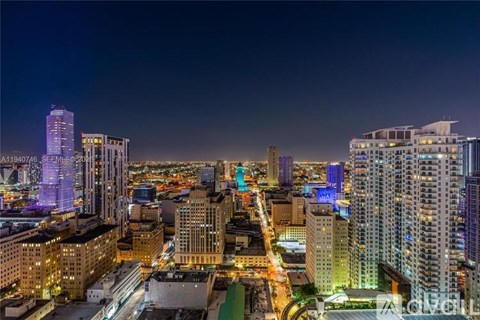 A cityscape at night with tall buildings and bright lights.