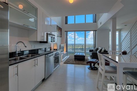 A modern kitchen with white cabinets and a large window overlooking the ocean.