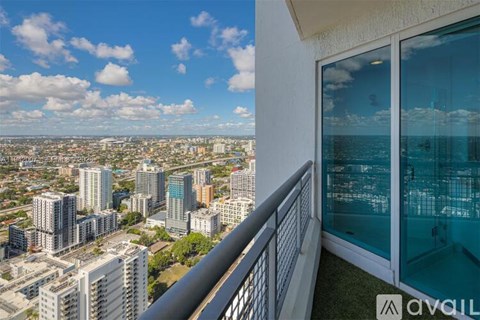 A balcony overlooks a cityscape with a clear blue sky above.