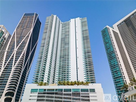 A group of tall buildings with a clear blue sky in the background.