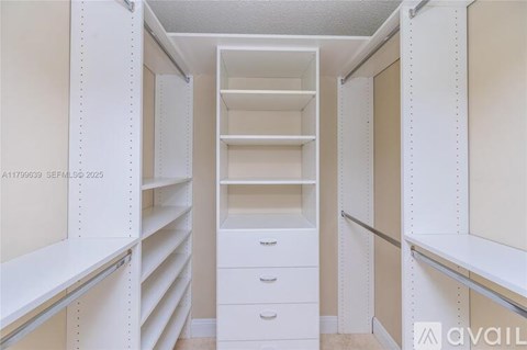 A white walk-in closet with shelves and drawers.