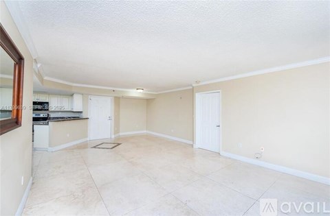 A spacious room with beige walls and a tiled floor.