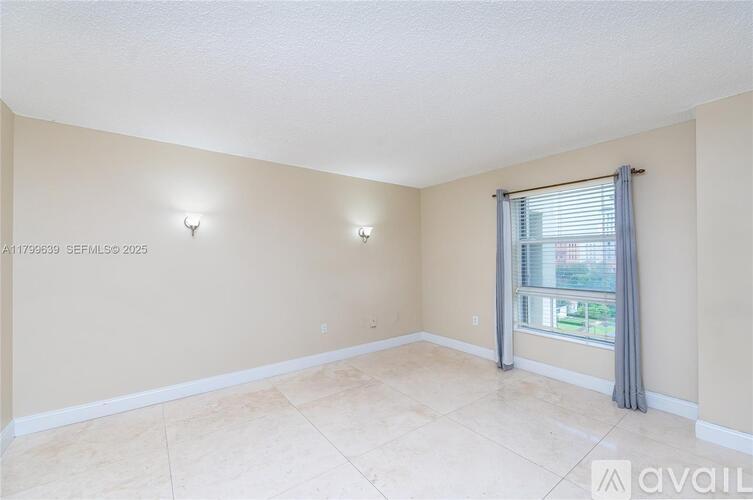 A room with beige walls and a large window with a grey curtain.