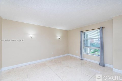 A room with beige walls and a large window with a grey curtain.