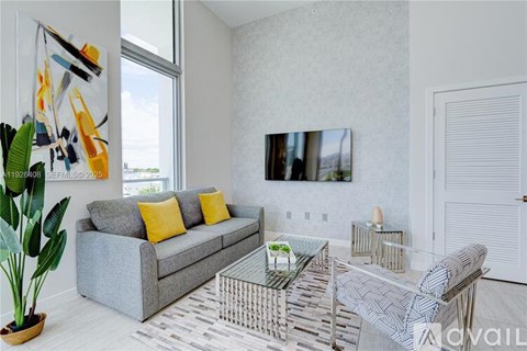 A living room with a grey couch, a glass coffee table, and a painting on the wall.