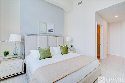 A bedroom with a large bed and a nightstand with a lamp.