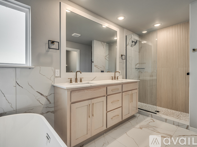 A bathroom with a marble countertop and a large mirror above the sink.