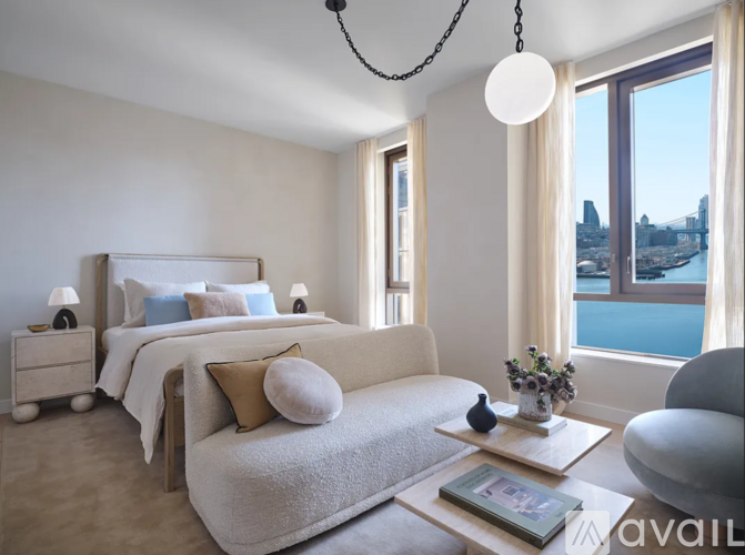 A bedroom with a large bed and a view of a city skyline through the window.