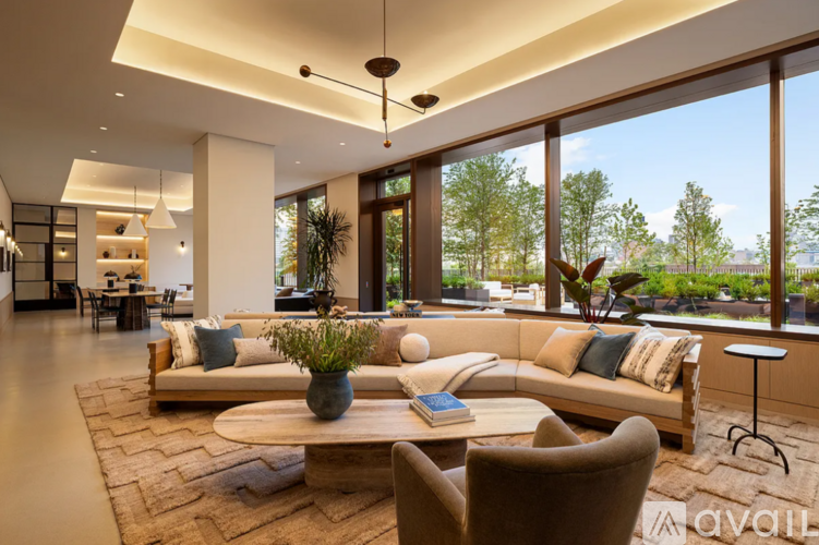 A living room with a large window, a sofa, a coffee table, and a potted plant.