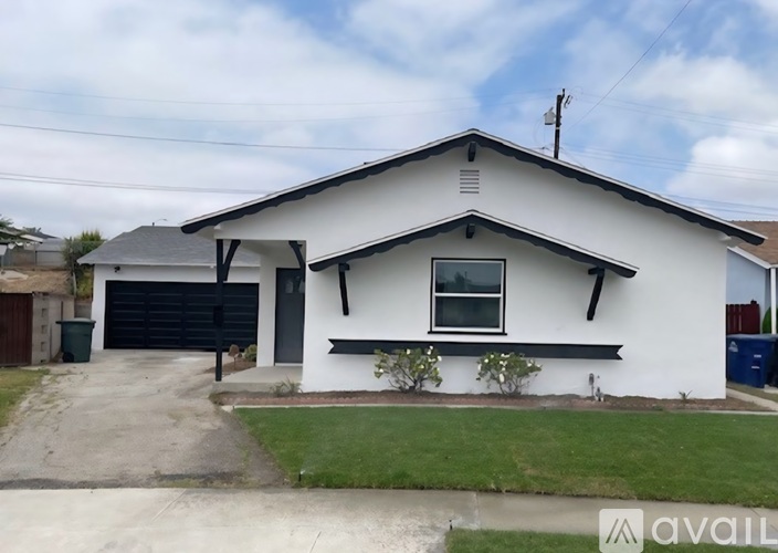 A white house with a black garage door and a small window above it.