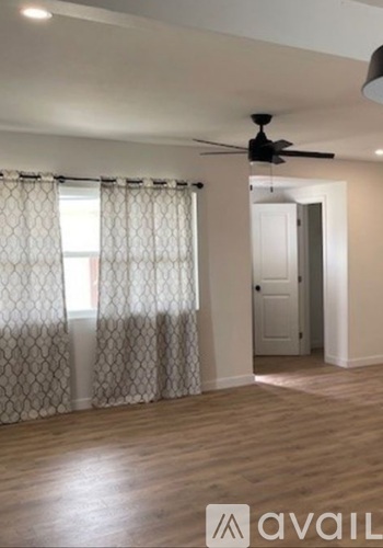 A room with a ceiling fan and a door leading to another room.