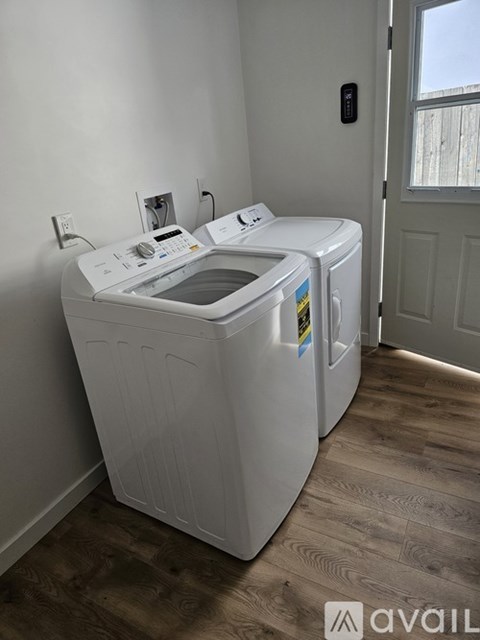 A white washing machine in a room with wooden flooring.