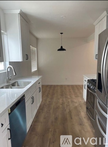 A kitchen with white cabinets and a wooden floor.