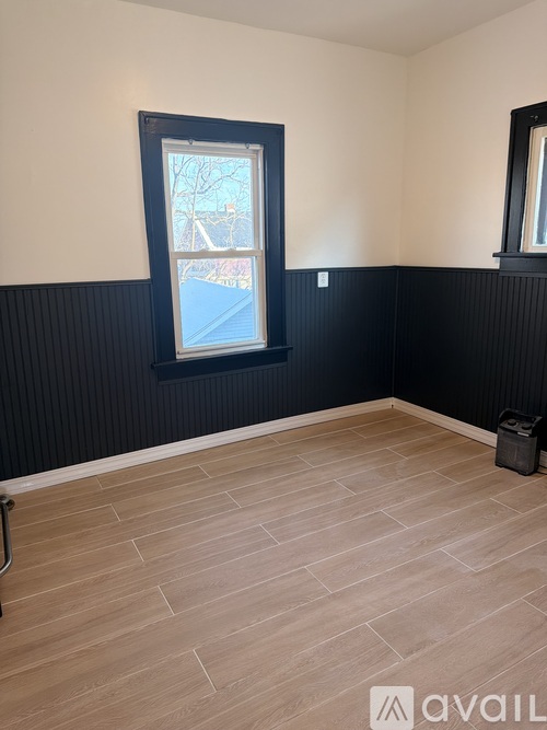 A room with a window and a wooden floor.