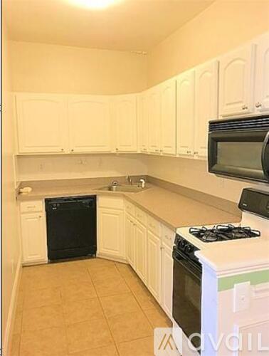 A kitchen with white cabinets and a black dishwasher.
