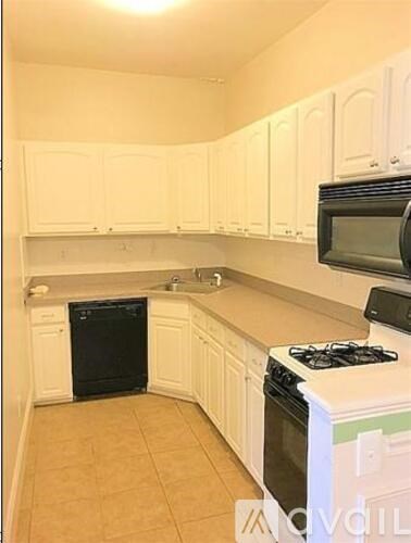A kitchen with white cabinets and a black dishwasher.