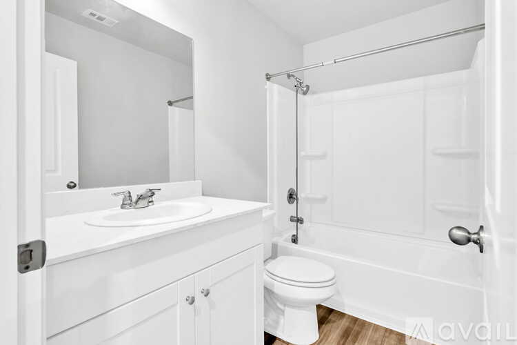 A white bathroom with a toilet, sink, and shower.