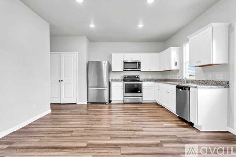A kitchen with white cabinets and a wooden floor.