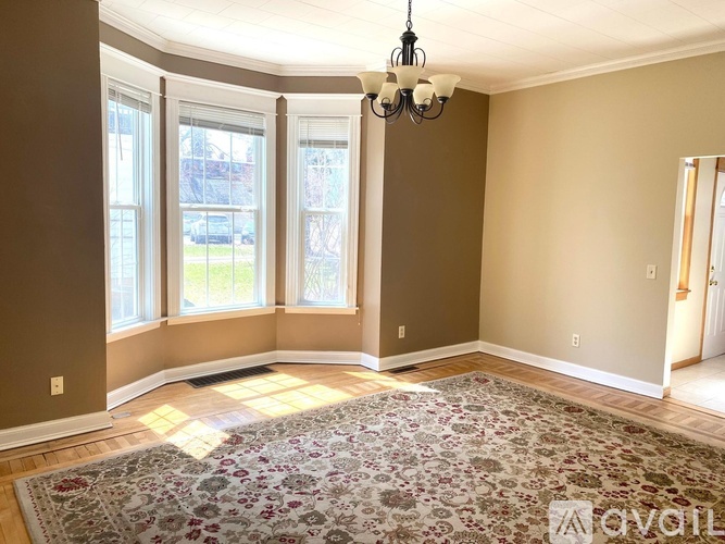 A room with a rug on the floor and a chandelier hanging from the ceiling.