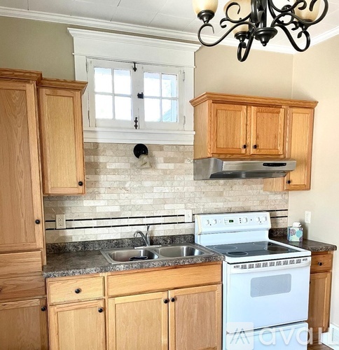 A kitchen with wooden cabinets and a white stove top oven.