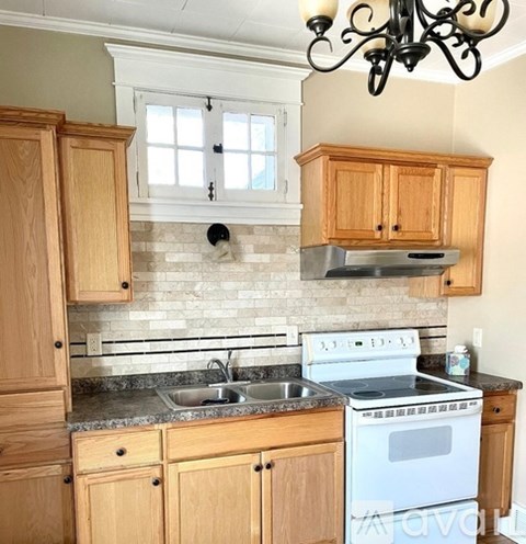 A kitchen with wooden cabinets and a white stove top oven.