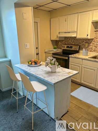 A kitchen with a marble island and white cabinets.