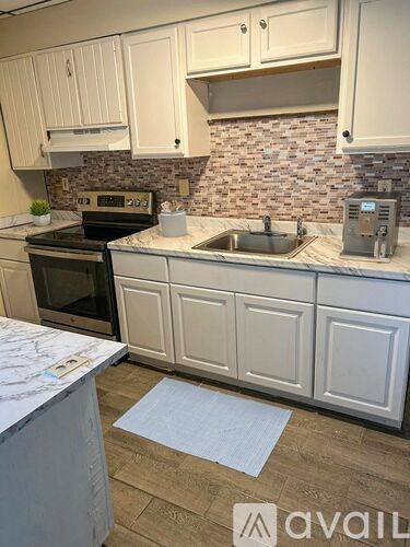 A kitchen with white cabinets and a marble countertop.