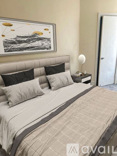 A bed with a grey headboard and a painting above it.