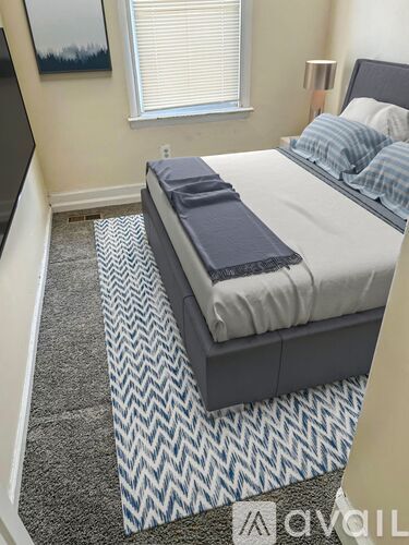 A bedroom with a bed, pillows, and a carpet.
