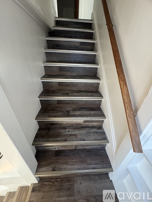 A wooden staircase with a metal handrail.