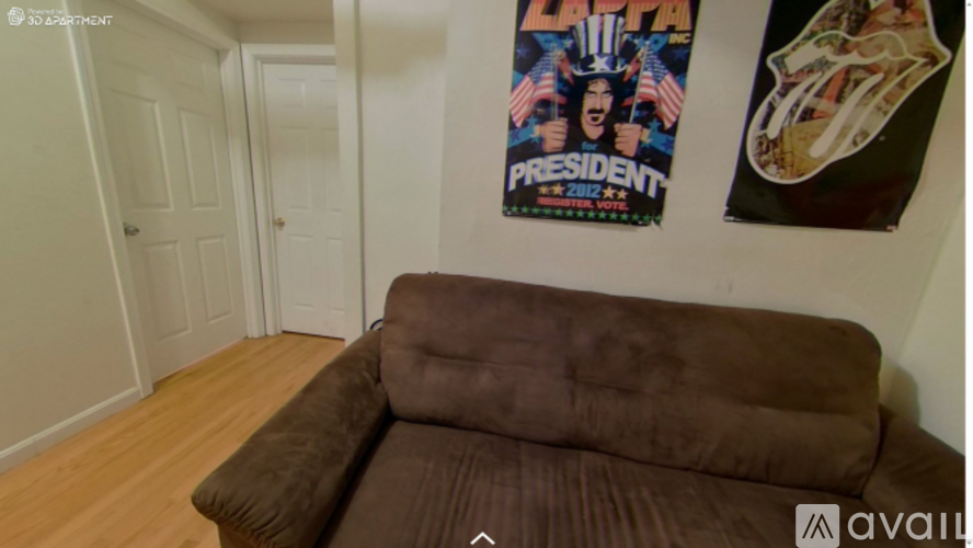 A brown couch in a room with a poster on the wall.