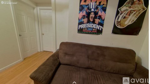 A brown couch in a room with a poster on the wall.