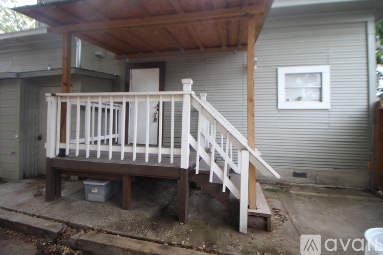 A wooden deck with a bench and a staircase leading to a house.