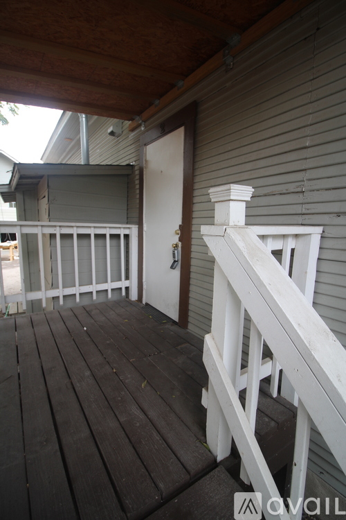 A wooden deck with a white railing and a door.