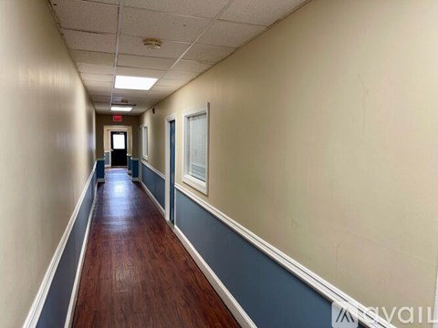 A long hallway with a red exit sign at the end.