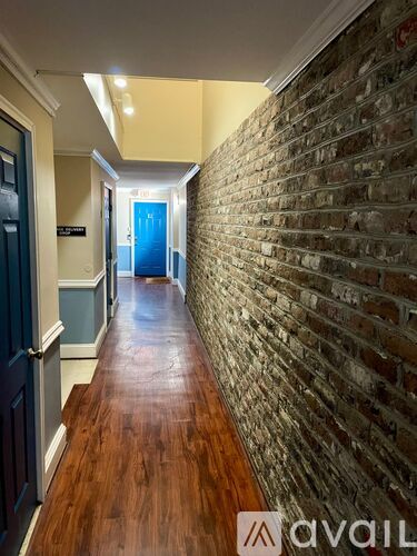 A hallway with a brick wall on one side and a blue door at the end.