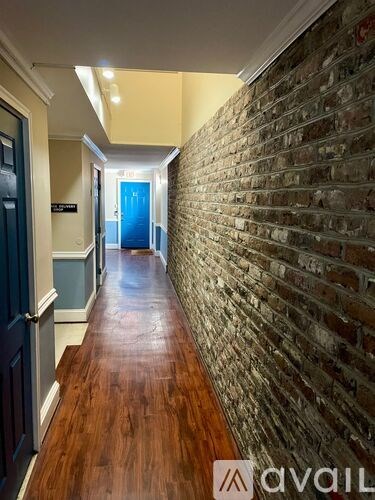 A hallway with a brick wall on one side and a blue door at the end.