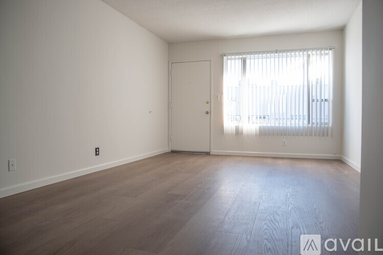 A room with wooden flooring and a door leading to a hallway.