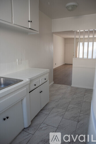 A kitchen with white cabinets and a marble floor.