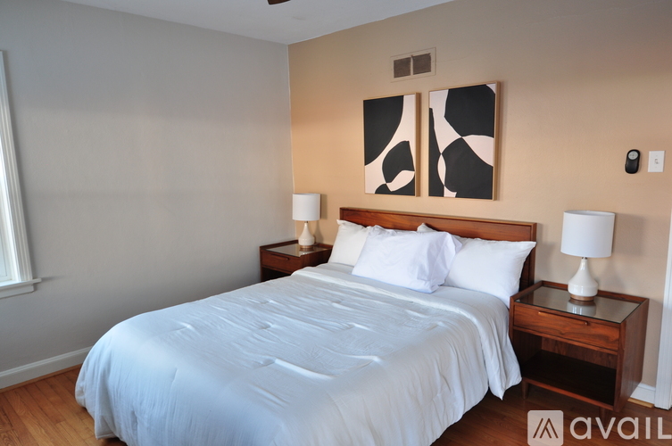 A bedroom with a large bed and two lamps.