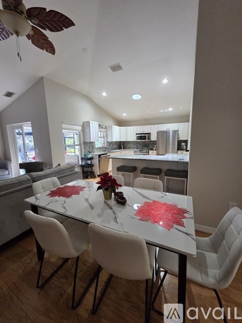 A modern kitchen with a dining table set with white chairs and a flower centerpiece.