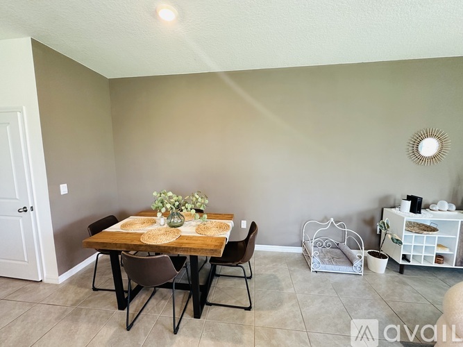A dining room with a table set for four and a white cabinet with glass doors.