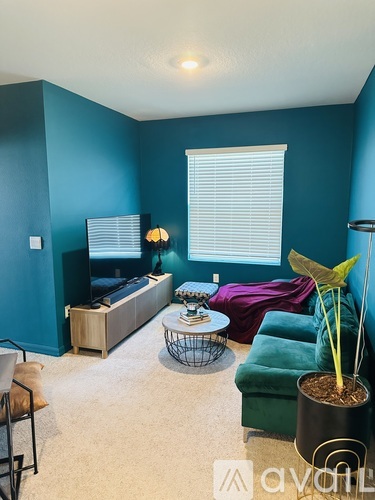 A living room with a green couch and a plant.