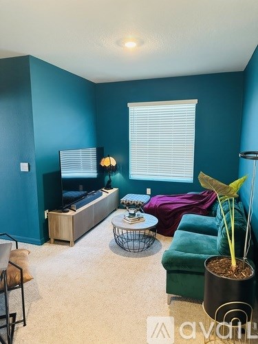 A living room with a green couch and a plant.