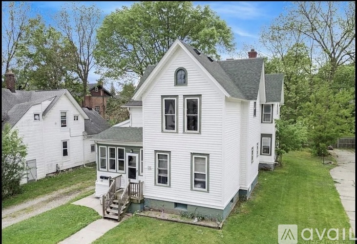 A white house with a grey roof and a small porch.