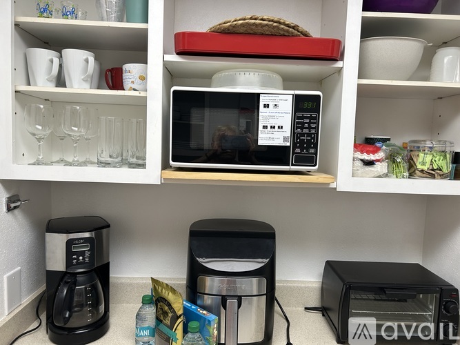 A microwave with a digital clock showing 12:21 is sitting on a shelf in a kitchen.