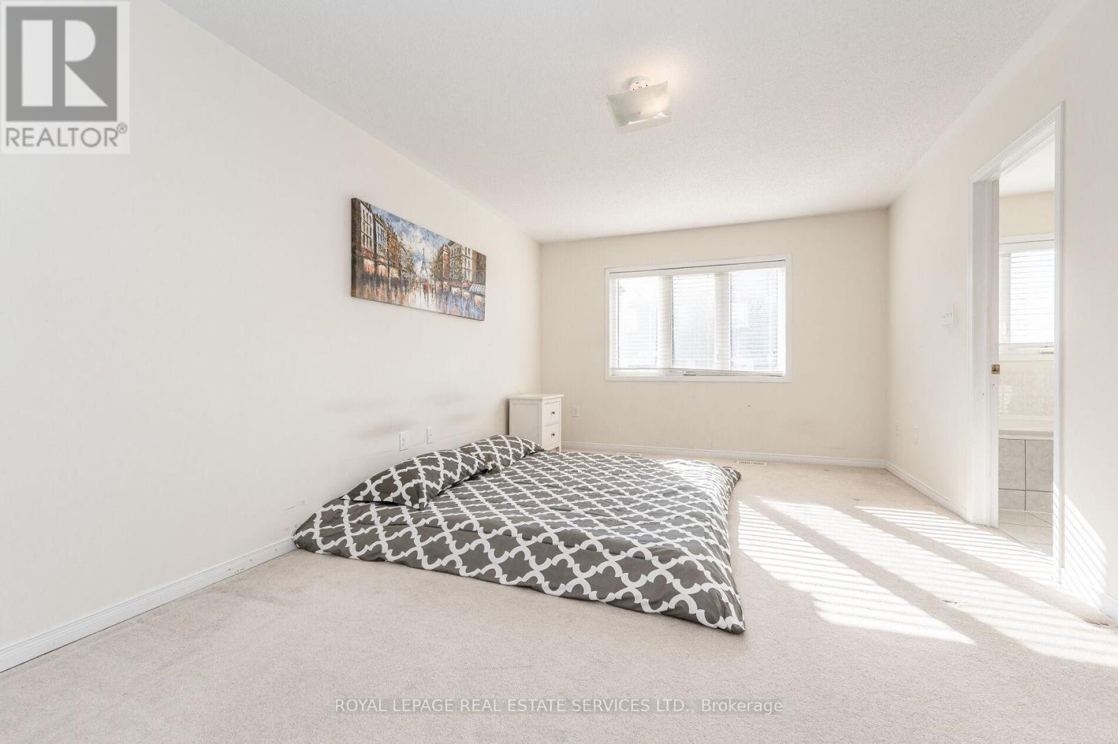 A bedroom with a large bed and a painting on the wall.