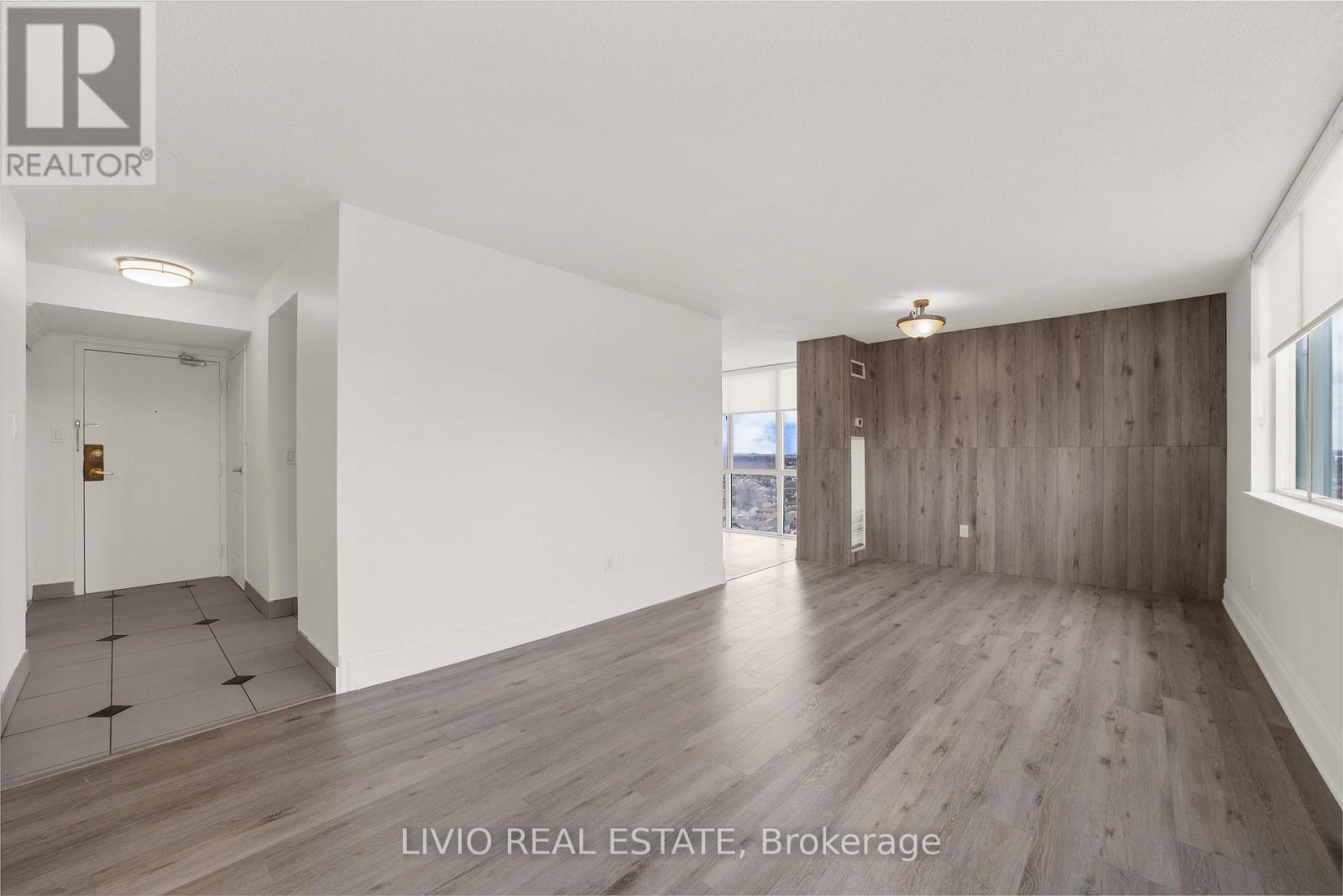 A spacious room with wooden flooring and white walls, presented by Livio Real Estate Brokerage.