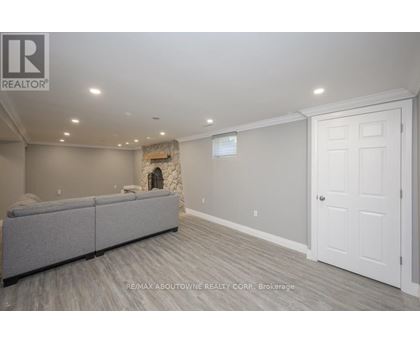A spacious living room with a grey sofa and a stone fireplace.