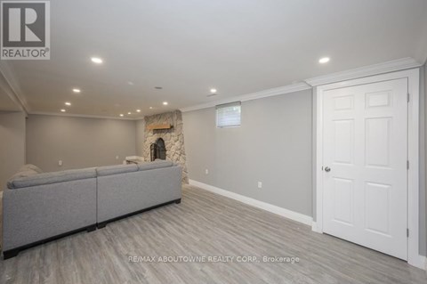 A spacious living room with a grey sofa and a stone fireplace.